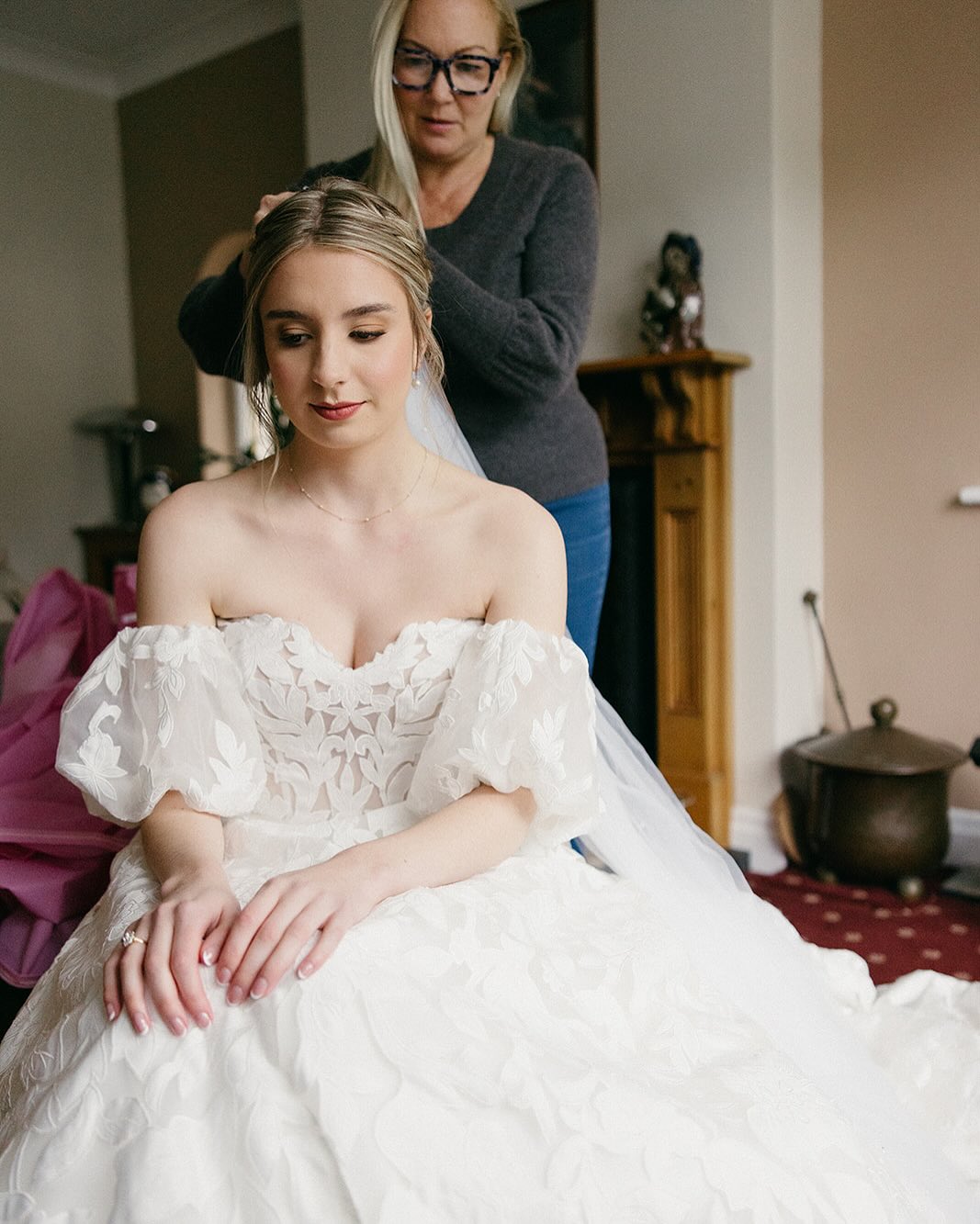 Our hairstylist setting the veil for a bride in a lace gown with soft glam