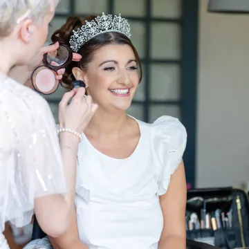 Our make-up artist brushing blush onto the laughing tiara bride