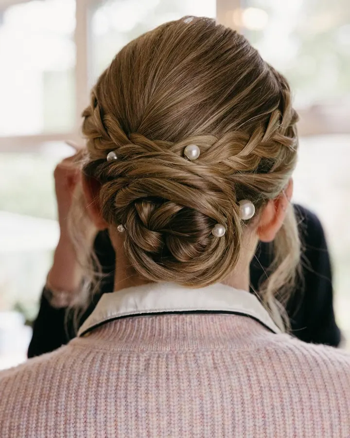Back view of a braided, wrapped low chignon with pearl pins