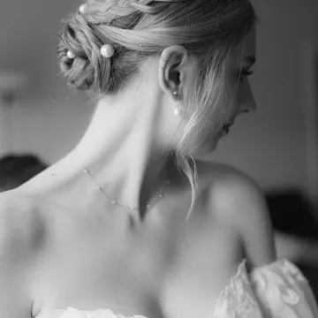 Black-and-white profile of a braided low bun with oversized pearl pins