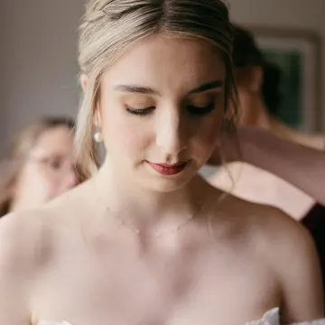 Bride with eyes lowered: a warm gold-brown lid, fluttery lashes and a matte berry-rose lip