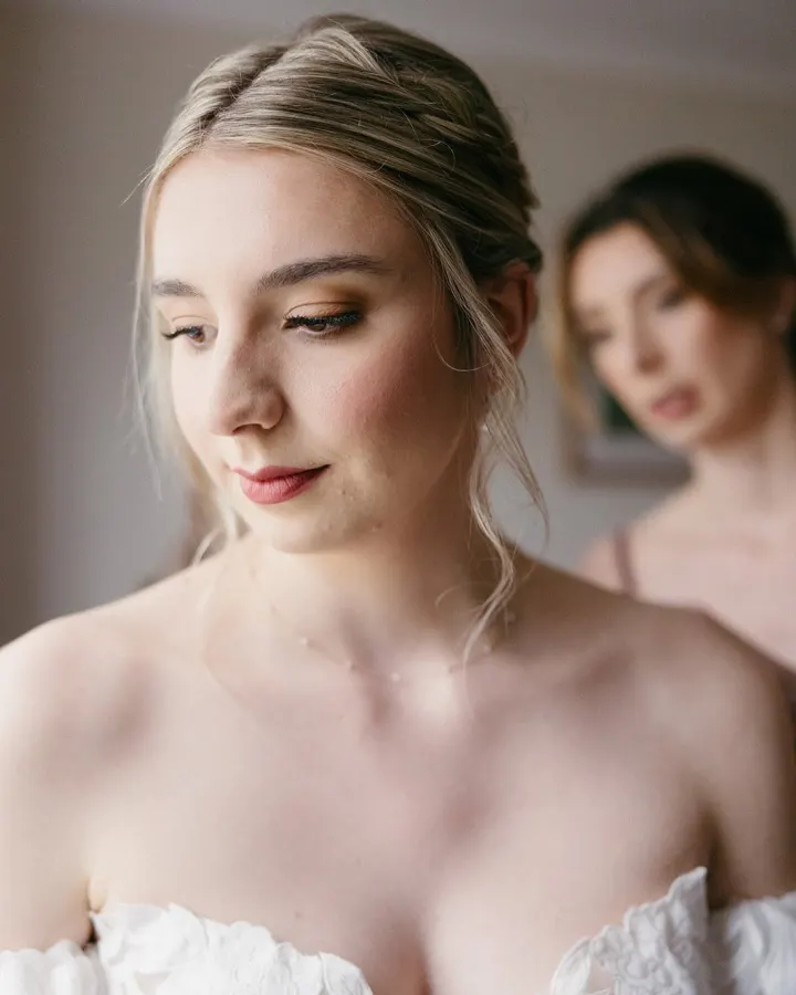 Three-quarter portrait: a bronze shimmer lid, soft flush, rose lip and loose face-framing tendrils