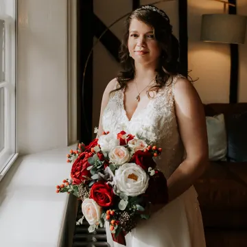 The tiara bride at the window, looking to camera, with half-up curls and a veil