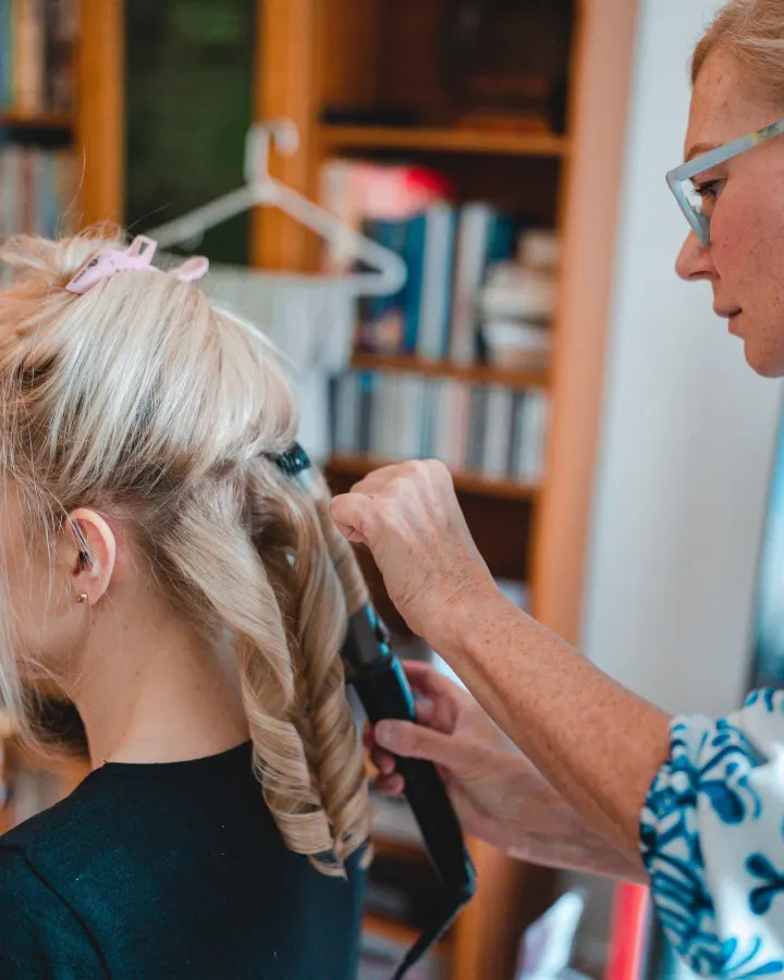 Our hairstylist curling long blonde hair with tongs