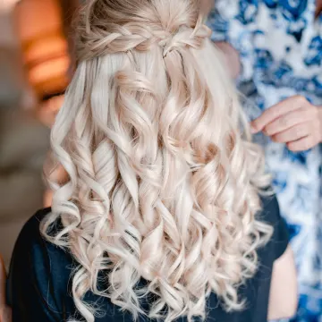 Back view of a half-up braided crown over loose ringlet curls